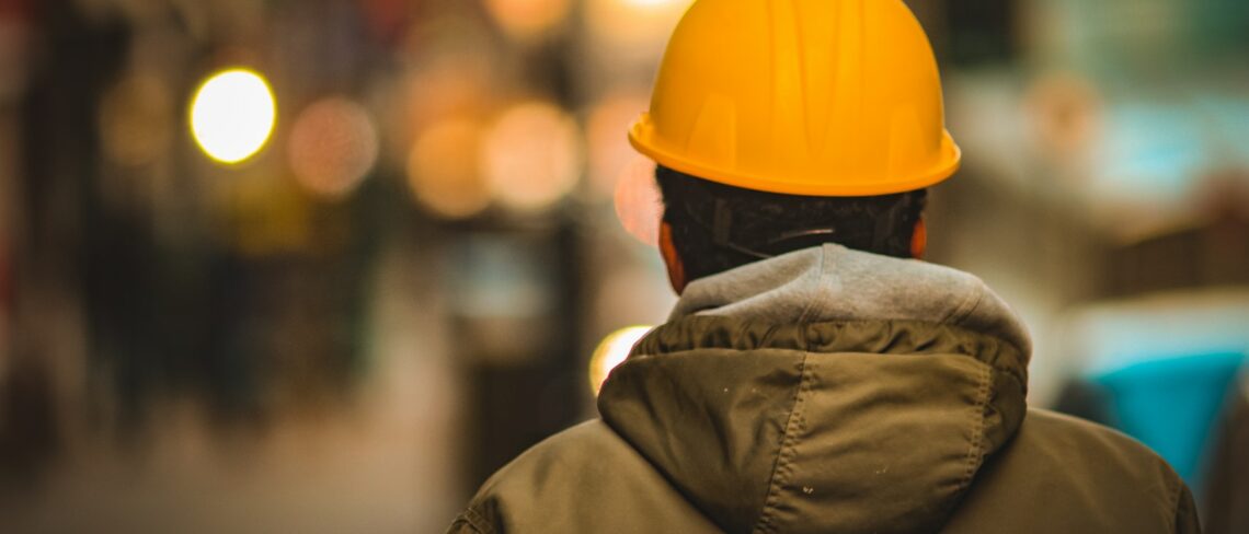 person in yellow hard hat and brown jacket